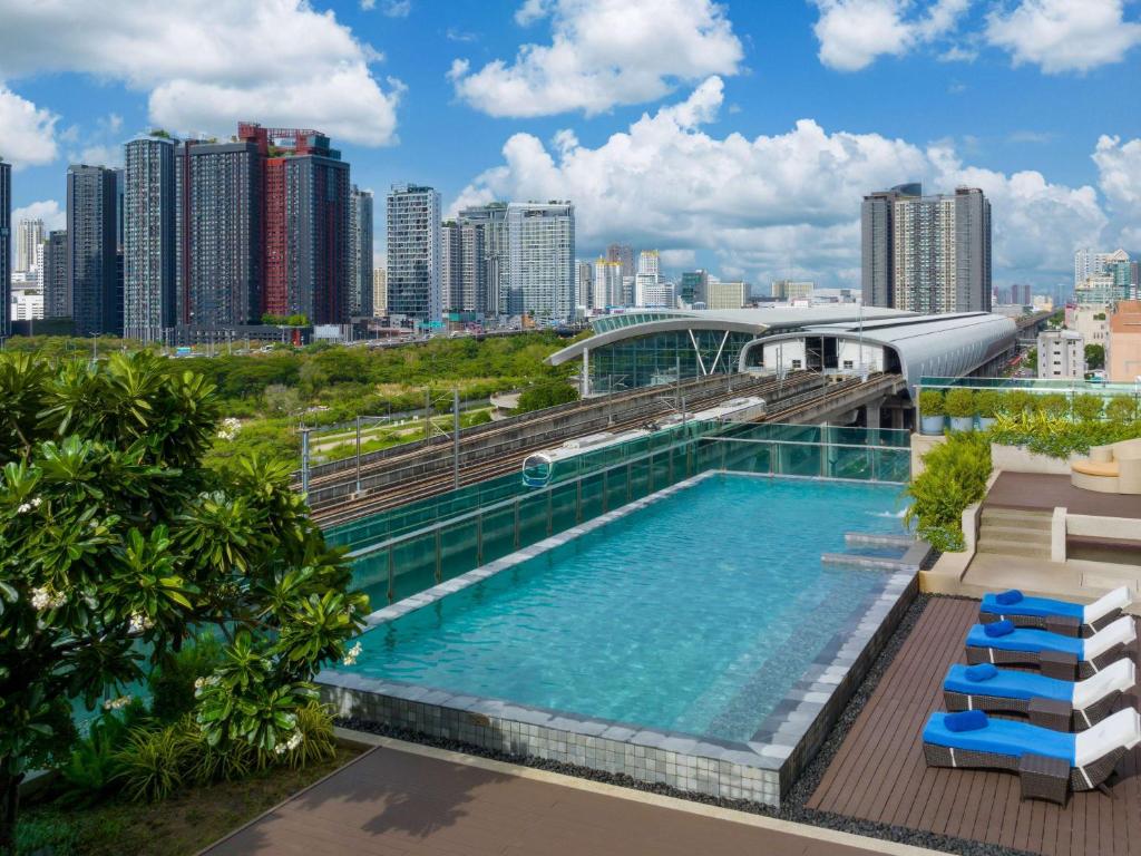 ein Schwimmbad auf dem Dach eines Gebäudes mit einer Stadt in der Unterkunft Mercure Bangkok Makkasan in Bangkok