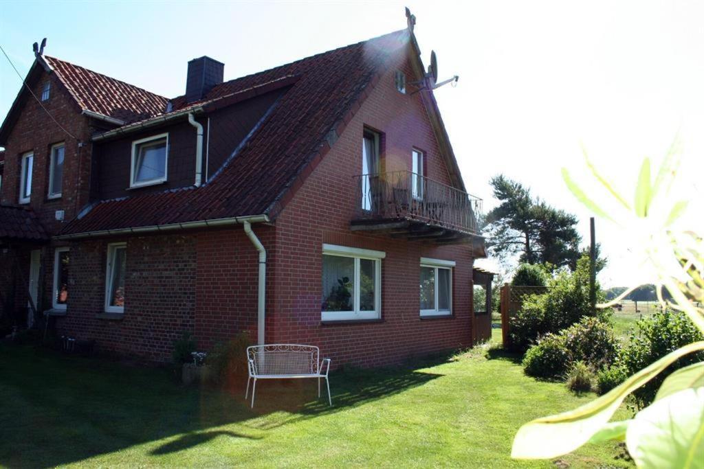 een rood bakstenen huis met een bank in de tuin bij Ferienwohnungen Bauernhof Beckmann in Winsen