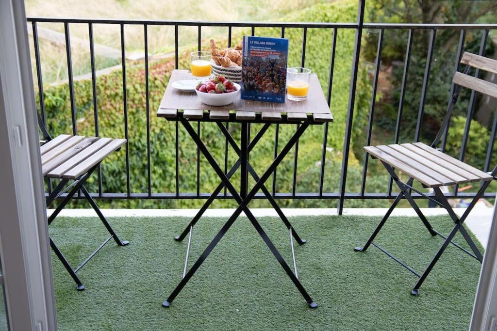 einen Tisch mit Essen und zwei Stühle auf dem Balkon in der Unterkunft Stade de France 6 pers in Saint-Denis