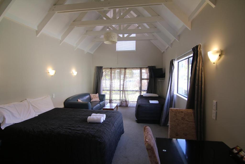 a bedroom with a bed and a living room at Apex on Fenton in Rotorua