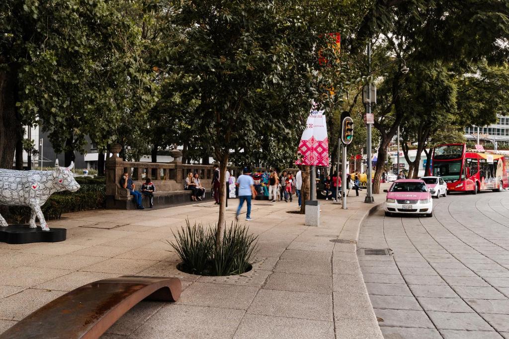 uma rua com uma estátua de uma vaca no passeio em Las Alas em Cidade do México