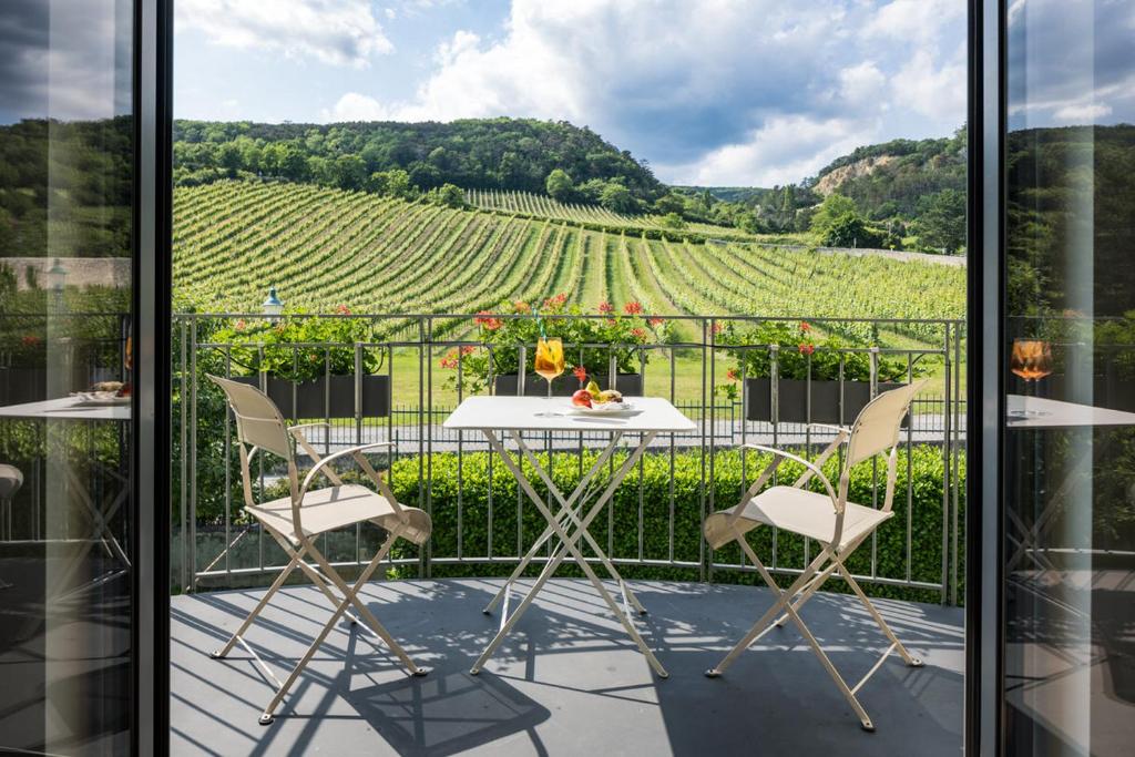 a balcony with a table and chairs and a view of a vineyard at Hotel Turmhof in Gumpoldskirchen