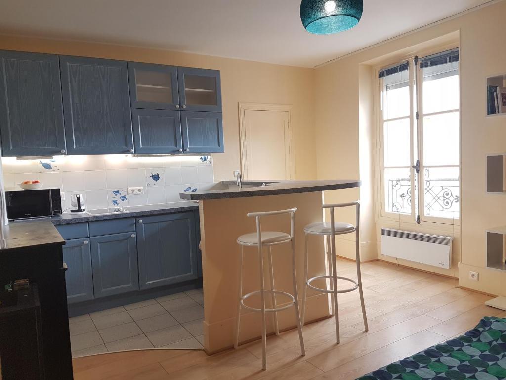 une cuisine avec des placards bleus et des tabourets de bar dans l'établissement Studio près de la tour Eiffel, à Paris