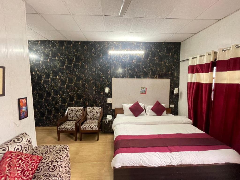 a hotel room with two beds and a chair at Hotel Amar in Mussoorie