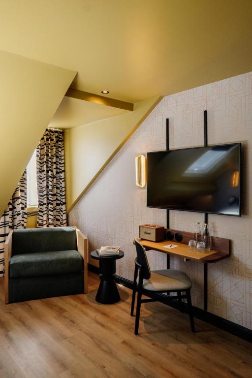 a living room with a couch and a table and a chair at Hôtel Riesner in Paris