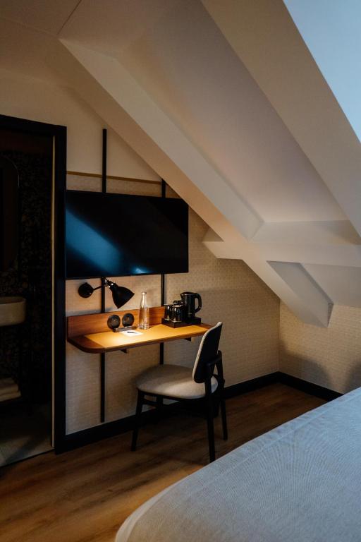 a bedroom with a desk in a room with an attic at Hôtel Riesner in Paris