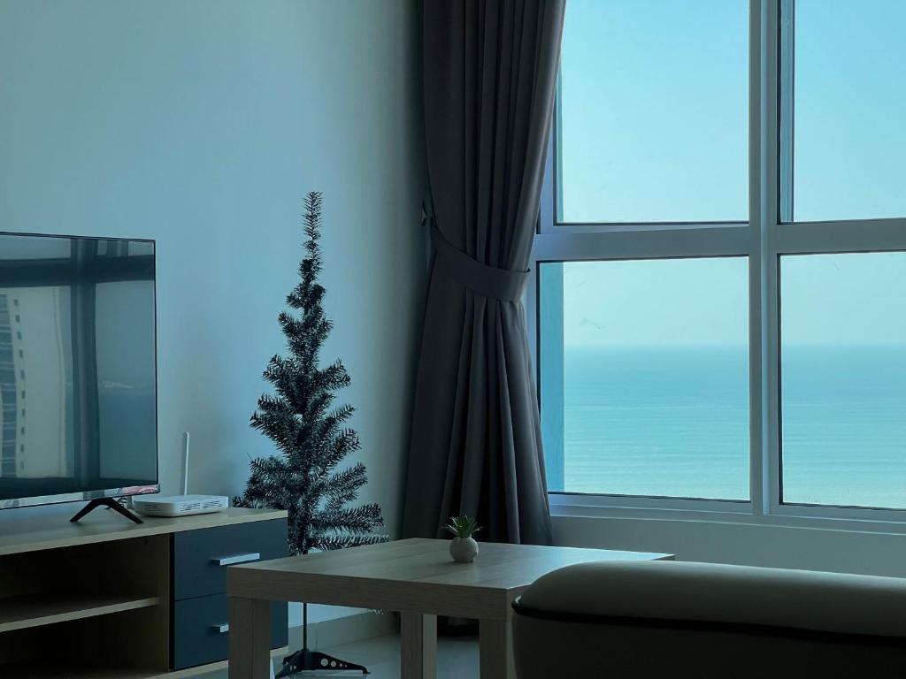 ein Wohnzimmer mit einem Weihnachtsbaum und einem Tisch in der Unterkunft Seaview Private Master Bedroom in a Shared Unit in Tanjong Tokong