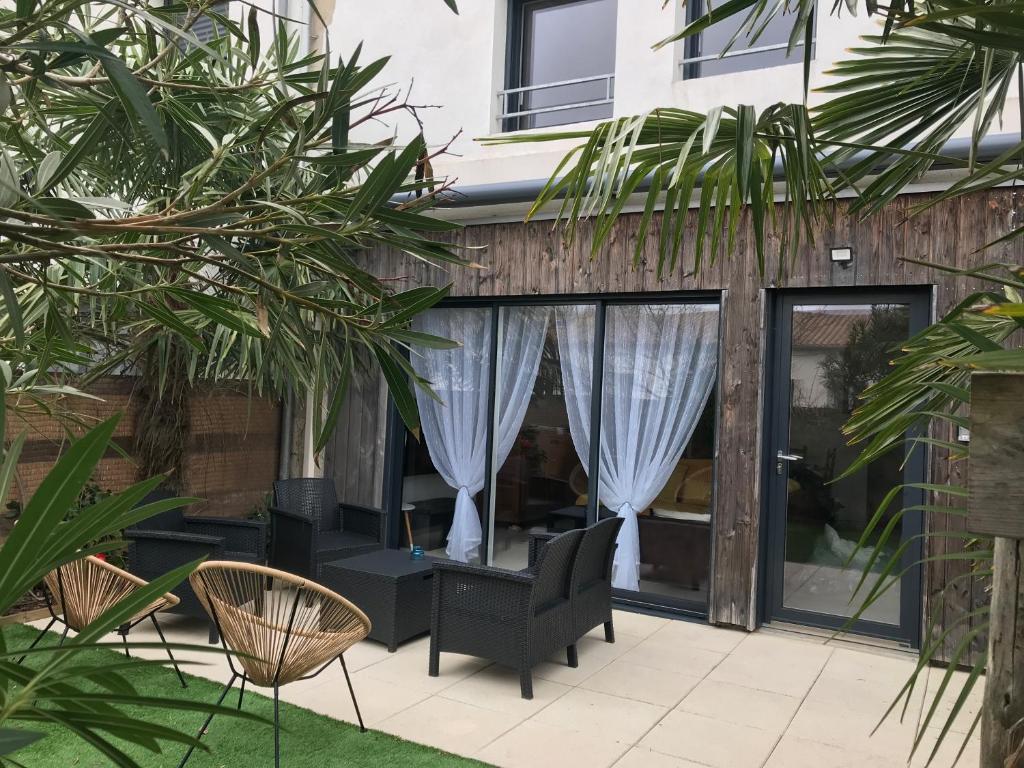 d'une terrasse avec des chaises noires et des rideaux blancs. dans l'établissement LES CAMELIAS N 4 maison de 80m2 à 5 minutes de l'île de Ré la rochelle et de la plage, à La Genilliere