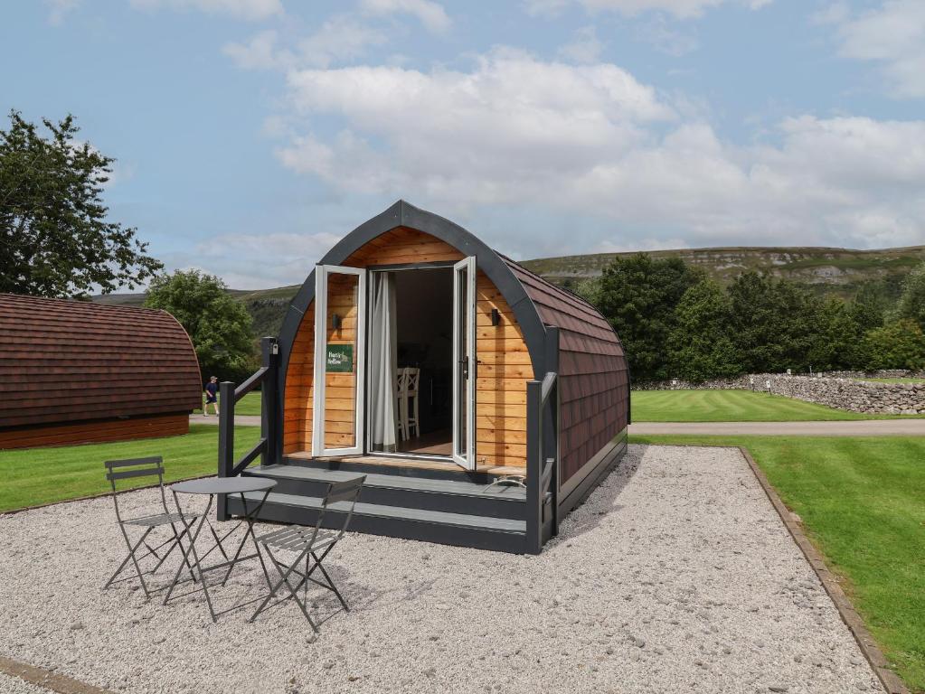 a tiny house with a porch and two chairs at Hare's Hollow in Skipton