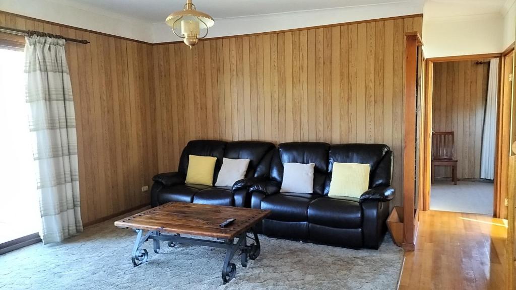 a living room with a leather couch and a coffee table at Surfside two-bedroom holiday upstairs in Batemans Bay