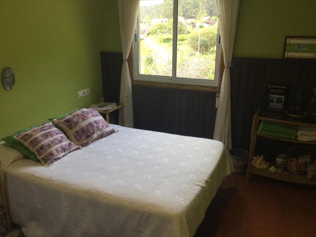 een bed met 2 kussens in een kamer met een raam bij Habitación en A Armenteira ideal peregrinos in Meis