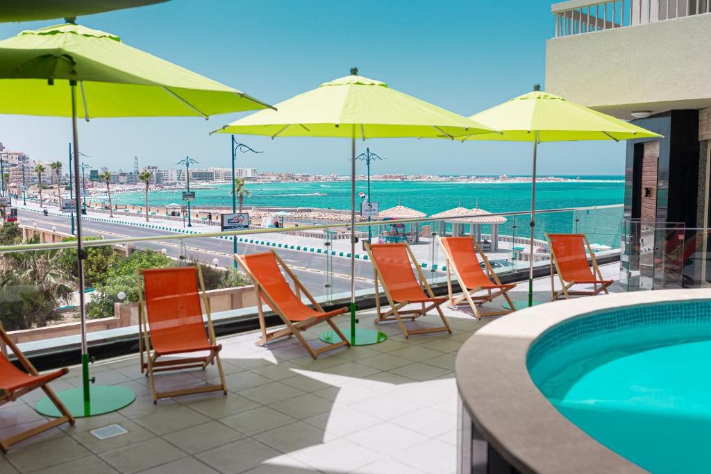 - un groupe de chaises longues et de parasols à côté de la piscine dans l'établissement Delmar Hotel Matrouh, à Marsa Matruh