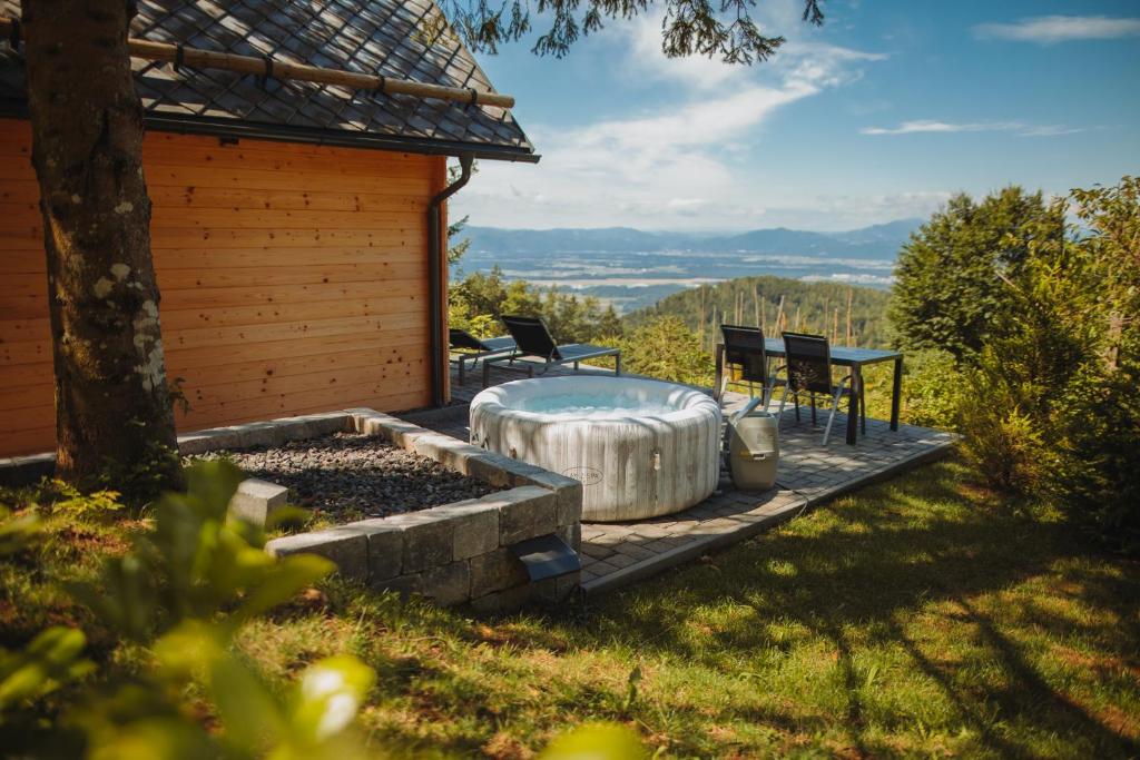 une cour avec un bain à remous, une table et des chaises dans l'établissement Med smrekami - Studio apartment with Chalet, Sauna and Jacuzzi, à Cerklje na Gorenjskem