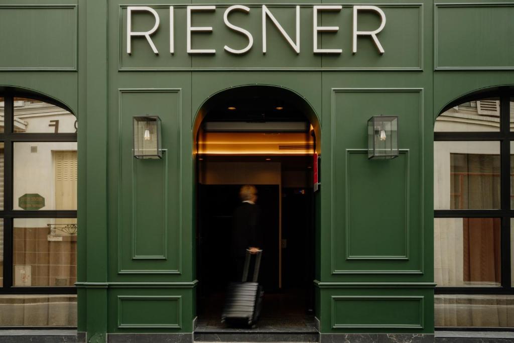 a woman standing in the doorway of a green building at Hôtel Riesner in Paris
