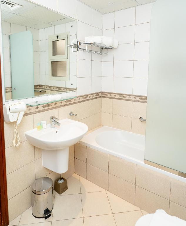 a bathroom with a sink and a bath tub at Al Raya Hotel Apartments in Dubai