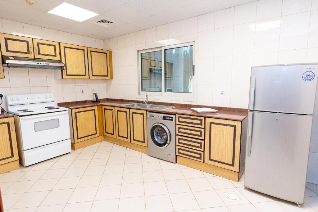 a kitchen with white appliances and wooden cabinets at Al Raya Hotel Apartments in Dubai