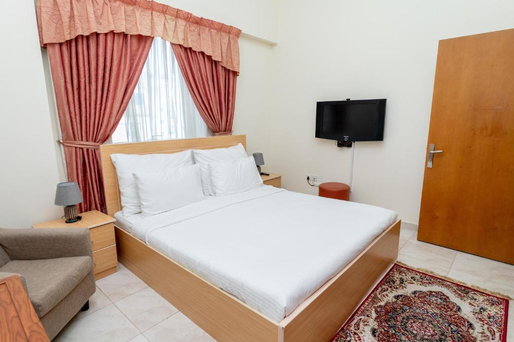 a bedroom with a bed and a couch and a window at Al Raya Hotel Apartments in Dubai