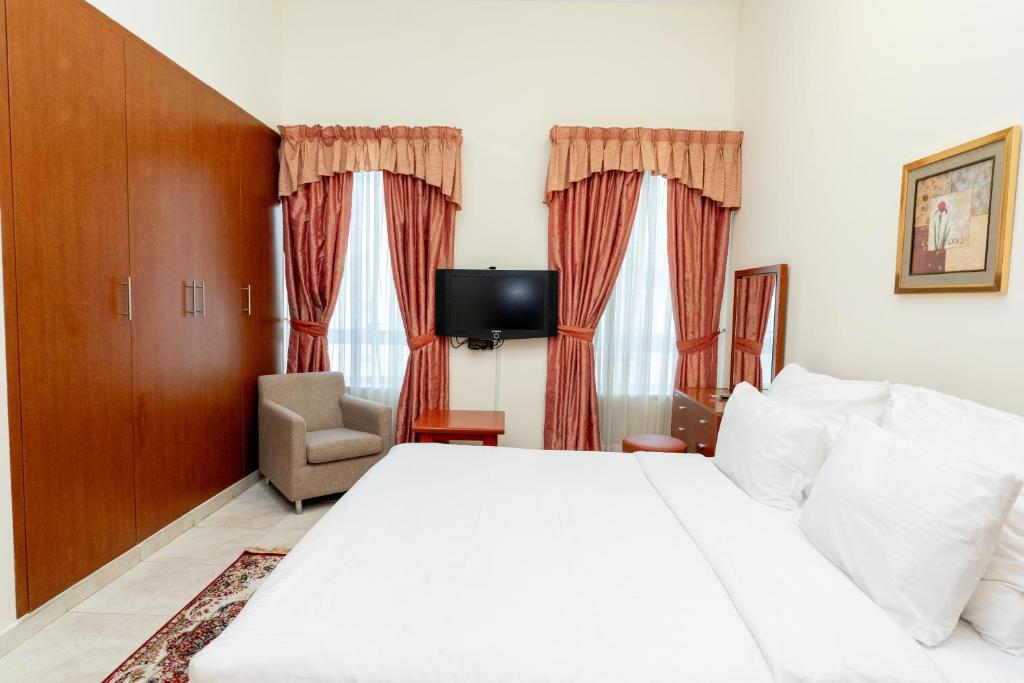 a bedroom with a large white bed and a chair at Al Raya Hotel Apartments in Dubai