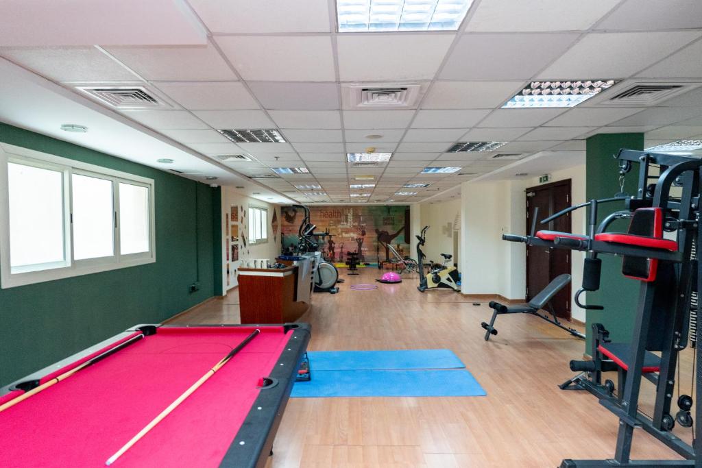 a gym with a pool table and exercise equipment at Al Raya Hotel Apartments in Dubai