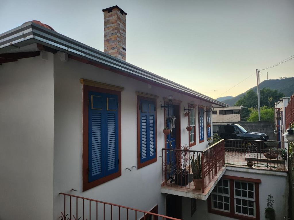 ein weißes Haus mit blauen Fensterläden und einem Balkon in der Unterkunft Solar dos Reis - Apartamento Turmalina in Ouro Preto