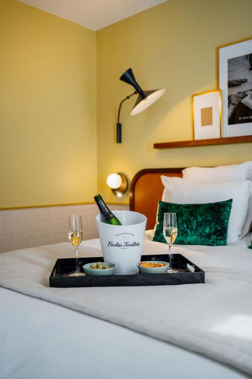 a tray of food and wine glasses on a bed at Hôtel Riesner in Paris