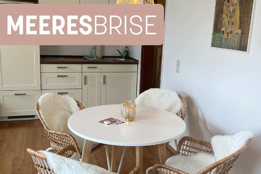 a white table in a kitchen with wicker chairs at Meeresbrise in Harrislee