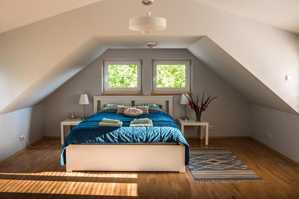 a bedroom with a bed with a blue comforter and two windows at Cottage house Lublin in Lublin