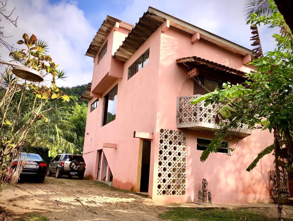 a pink house with cars parked in front of it at Lepá com Cozinha privativa in Boicucanga