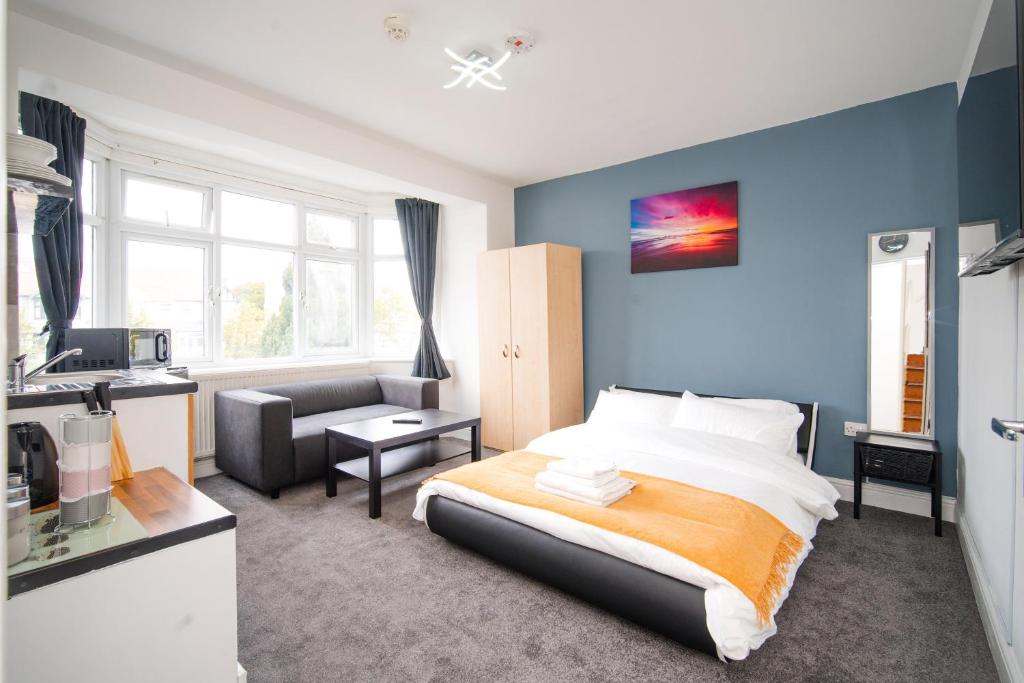 a bedroom with a bed and a living room with a couch at Modern private Double en-suite room2 in Barkingside