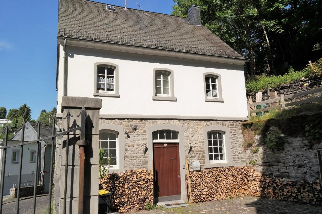 uma antiga casa de pedra com uma porta vermelha em Kutscherhaus Monschau em Monschau