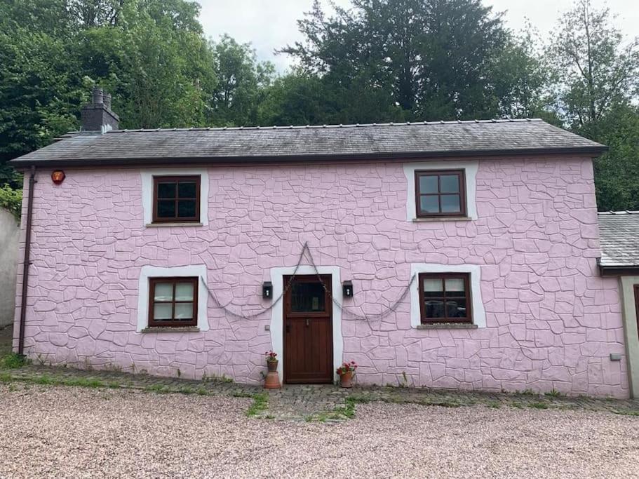 ein rosafarbenes Backsteinhaus mit einer Tür und Fenstern in der Unterkunft The Nest at the Pink Cottage in Carmarthen