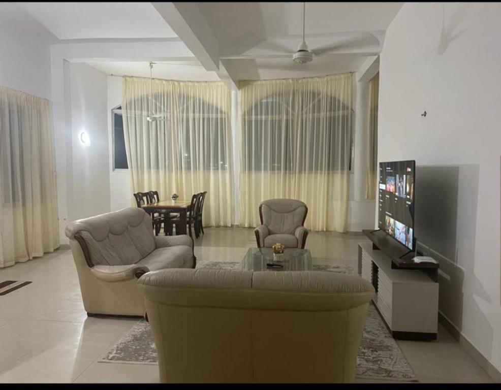 a living room with a couch and a tv and a table at Lux Suites Mkomani Beachfront Apartment in Mombasa