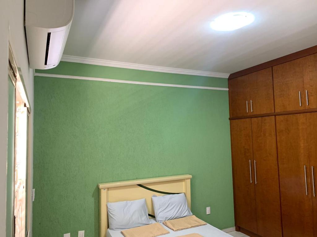 a bedroom with green walls and a bed with white pillows at Hostel Home Passos in Passos