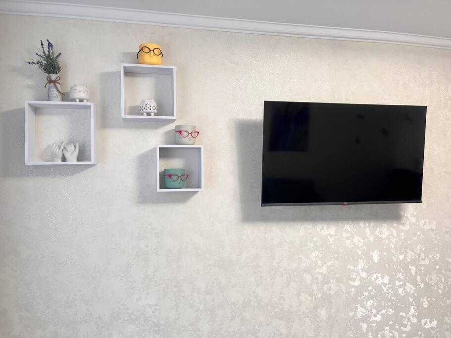 a flat screen tv hanging on a wall with shelves at 2-х комнатная квартира в центре in Almaty
