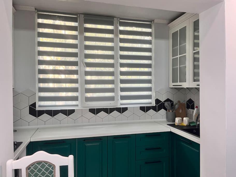 eine Küche mit grünen Schränken und einem Fenster in der Unterkunft 2-х комнатная квартира на Арбате in Almaty