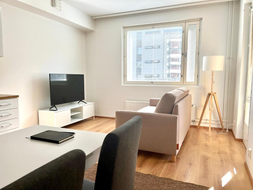 uma sala de estar com um sofá, uma mesa e uma televisão em Guest apartment with view and terrace, Vuosaari, Helsinki, self check-in em Helsinque
