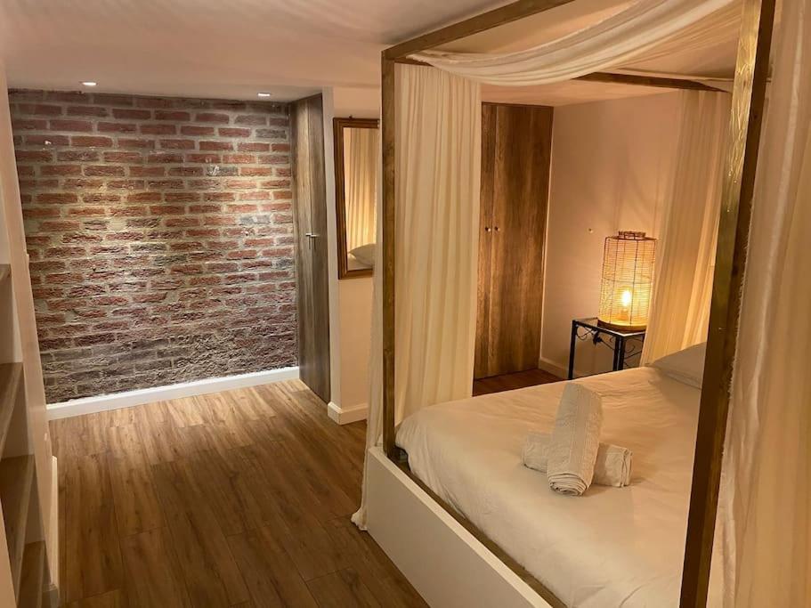 une chambre avec un lit et un mur de briques dans l'établissement Guest house privée, à Ézanville