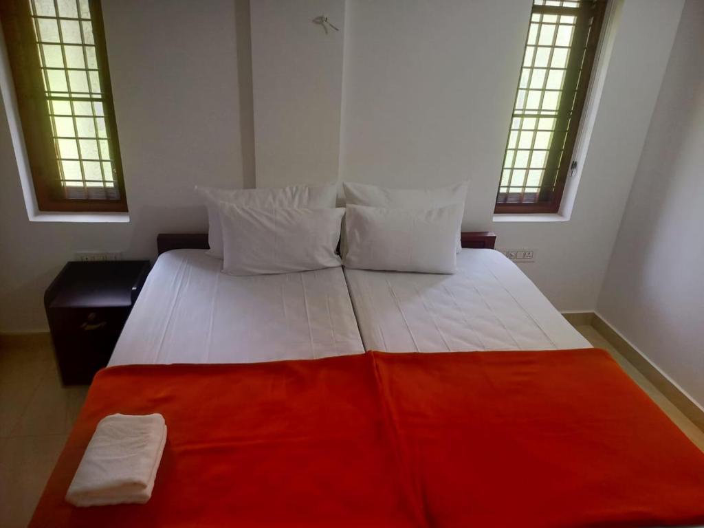 um quarto com uma cama grande e um cobertor vermelho em Grace Mary Residency em Nedumbassery