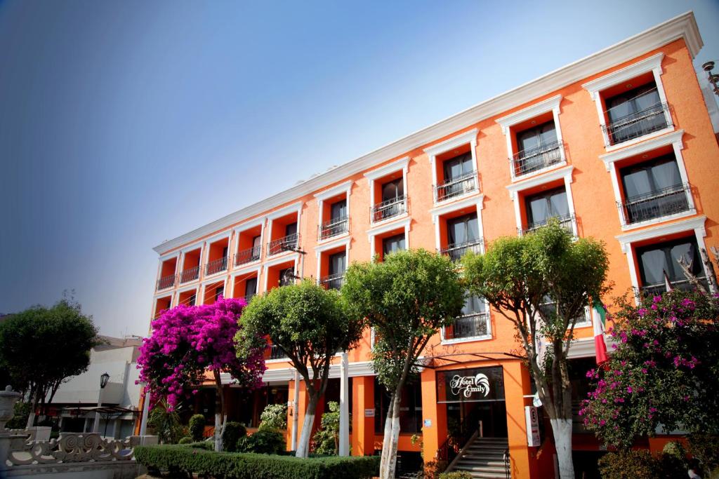 帕丘卡德索托的住宿－艾米麗酒店，一座橘色的建筑,前面有树木
