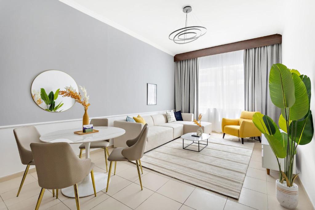 een woonkamer met een witte bank en een tafel en stoelen bij Silkhaus Luxurious Pool & Gym 1BDR Art Residence in Dubai
