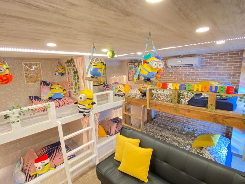 Pokój z 3 łóżkami piętrowymi i kanapą w obiekcie Orange House w Osace