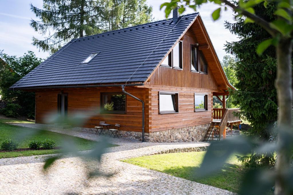 eine Holzhütte mit schwarzem Dach in der Unterkunft Moderní šumavská roubenka s výhledem na Boubín in Vimperk