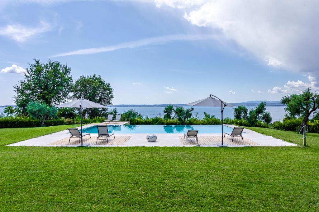 - une piscine avec des chaises, une table et un parasol dans l'établissement Villa Roccolo, à Calmasino