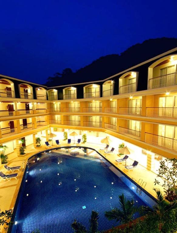 a large building with a large swimming pool at night at Kalim Resort in Patong Beach
