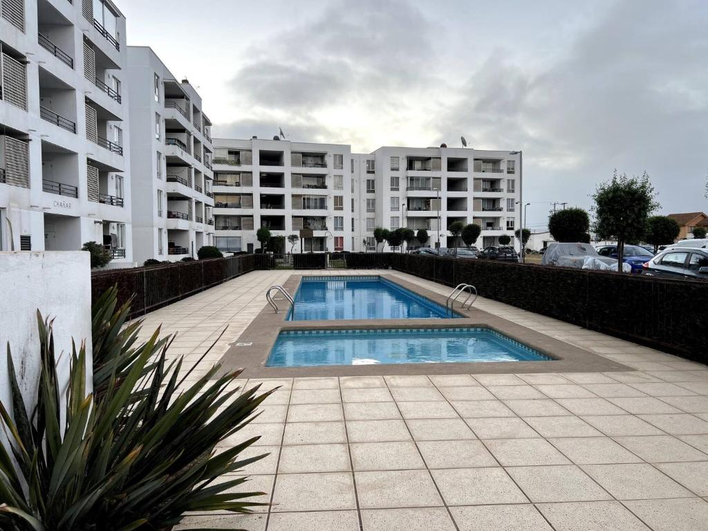 a swimming pool in front of some apartment buildings at Cozy Apartment Near Airport, Secure, and Versatile in La Serena