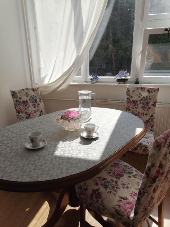 a dining room table with two chairs and a table with two cups at Flowers Apartment Tuzla in Tuzla