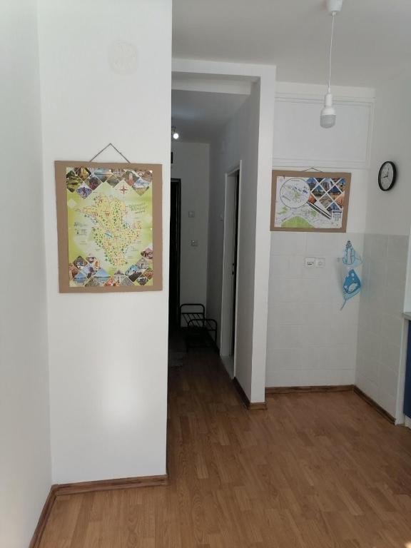 a hallway with white walls and a clock on a wall at Flowers Apartment Tuzla in Tuzla
