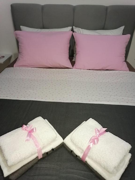 a bed with two white towels with pink bows at Flowers Apartment Tuzla in Tuzla