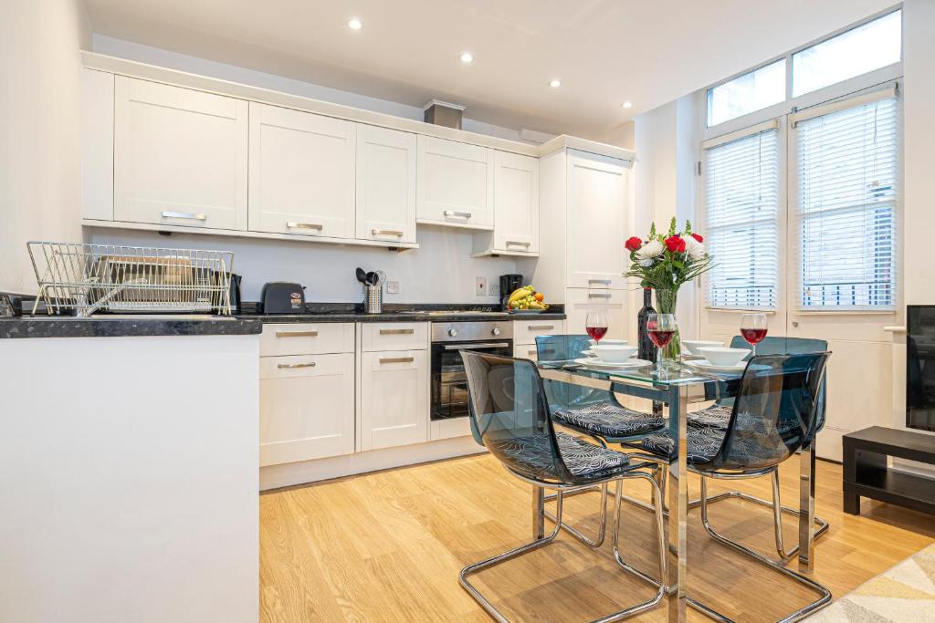 una cucina con tavolo in vetro e sedie di Turnmill Apartments a Londra