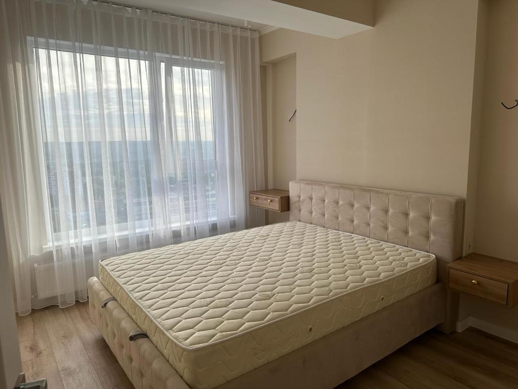 ein Bett in einem Schlafzimmer mit einem großen Fenster in der Unterkunft Loft Aparts in Chişinău